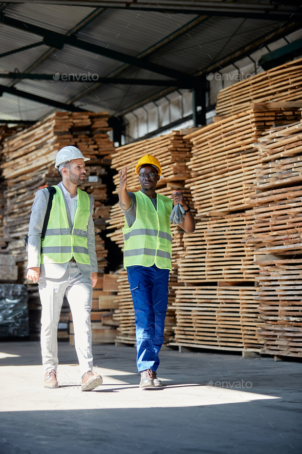 African American lumber worker talking to his manager while walking